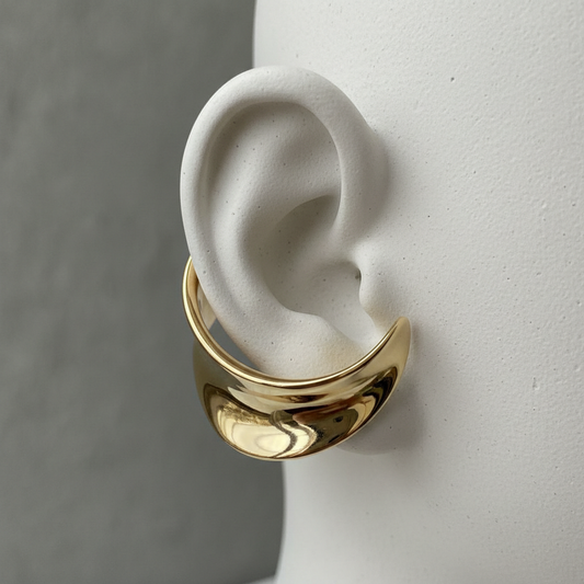 14kt gold ear cuff on ceramic ear display with warm studio lighting